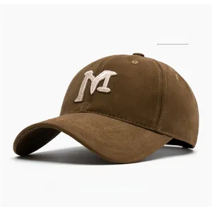 Detailed view of coffee cotton twill fabric with cream embroidered M logo and letters