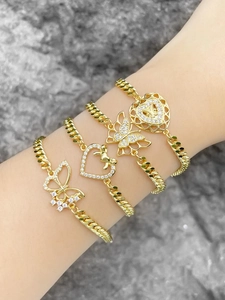 Detailed view of layered gold bracelets with butterfly and hollow heart zirconia charms