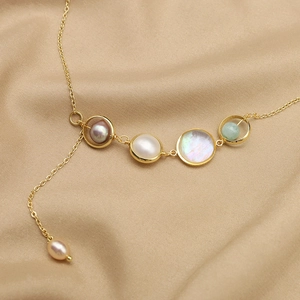 Asymmetric natural pearl necklace with purple gems and gold Y-chain on silk fabric