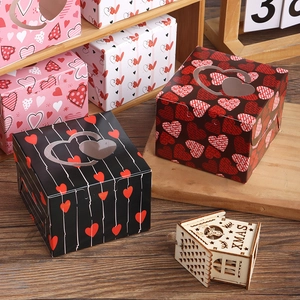 Square gift boxes with heart windows in black and red on a rustic wooden table