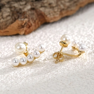 Detailed view of elegant gold stud earrings with suspended pearls in a cluster design