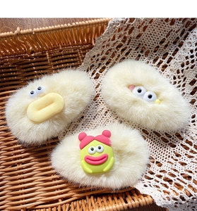 Detailed view of three cute plush hair clips with big eyes and cartoon monster designs