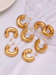 Detailed close-up of polished gold C-shape chunky hoop earrings with mirror finish