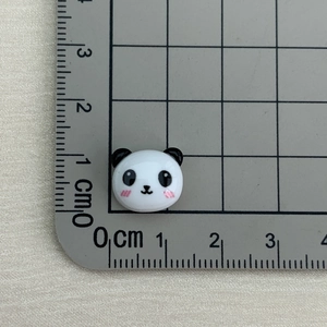 Close-up of a mini 1.5cm panda resin charm on a ruler showing precise small dimensions
