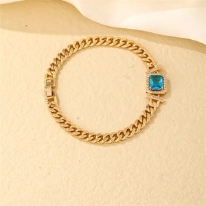 Detail of gold Cuban chain bracelet with a square blue zircon and pavé setting