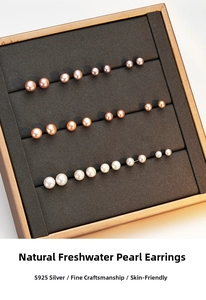 Detail of assorted natural freshwater pearl studs in white and pink on a grey velvet tray