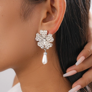 Detail shot of silver flower earrings with sparkling rhinestones and white teardrop pearl