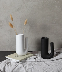 Gros plan de vases modernes en céramique blanc et noir mat en forme de U sur tissu