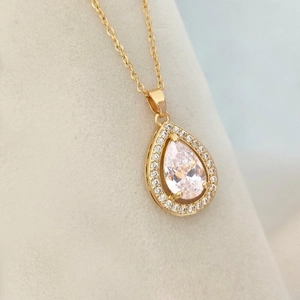 Elegant gold waterdrop pendant necklace with transparent cubic zirconia on grey velvet