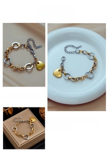 Detail view of two-tone gold and silver chain bracelet with a heart pendant on various displays