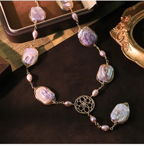 Macro shot of baroque pearls with pink luster and golden wire wrapping on velvet base