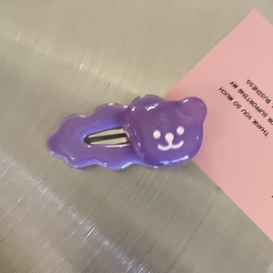 Purple cute bear wave edge hairpin made of resin shown on a textured background