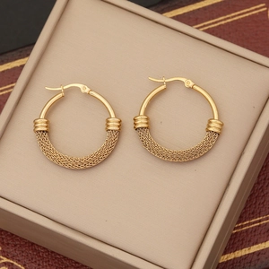 Detailed macro of gold hoop earrings with distinctive woven metal mesh texture finish