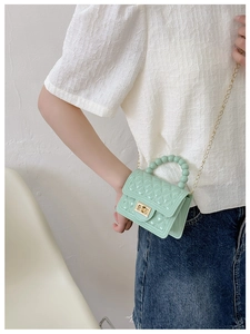 Detail of mint green jelly bag with pearl handle, gold chain strap and turn-lock closure