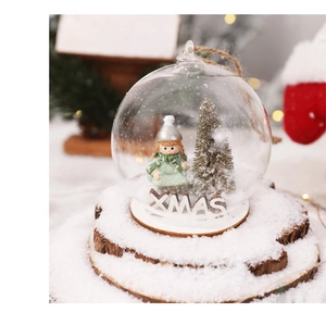 Close-up of LED Christmas glass ball with a girl figurine and snowy mini pine tree