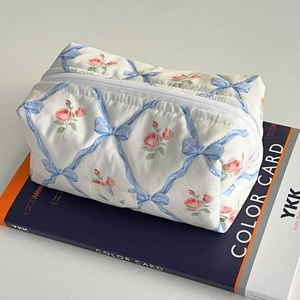 Detailed macro view of quilted cotton cosmetic bag with blue ribbons and pink floral pattern