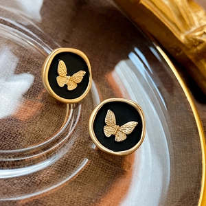 Detail of vintage butterfly stud earrings with gold edges and black enamel finish