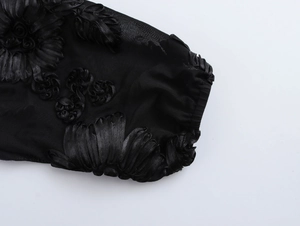 Macro view of black mesh sleeve featuring exquisite floral embroidery and fine lace texture