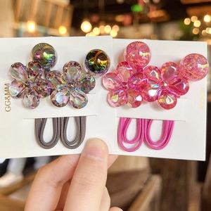Detail of colorful camellia flower hair ties in dark iridescent and pink crystal styles