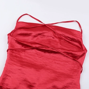 Detail of red satin dress featuring elegant criss-cross shoulder straps and neckline