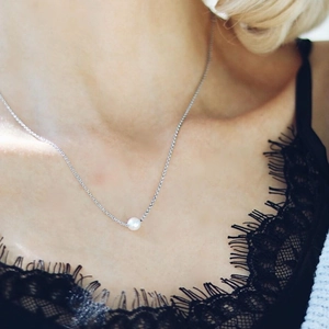 Elegant stainless steel necklace with a single round white pearl on a model