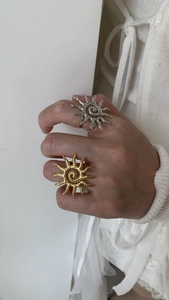 Detailed close-up of gold and silver sun-shaped open rings with hammered metal texture