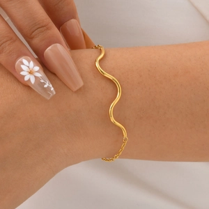 Detailed close-up of a wavy 18K gold-plated bracelet on a wrist with an adjustable chain