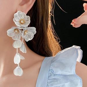 Détails des boucles d'oreilles pétales blancs ajourés avec de longs glands et cristaux