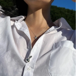 Outdoor natural lighting showing 925 silver layered necklaces with heart and bottle charms