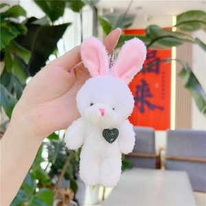 Gros plan d'un lapin en peluche avec un cœur tricoté et une chaîne à billes argentée