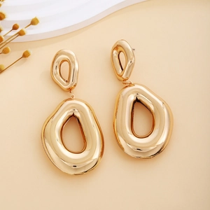 Close-up of golden hollow streamlined irregular earrings with high gloss metallic finish