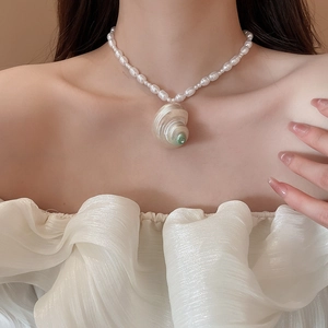 Detail of baroque pearl necklace with natural shell pendant worn on the collarbone