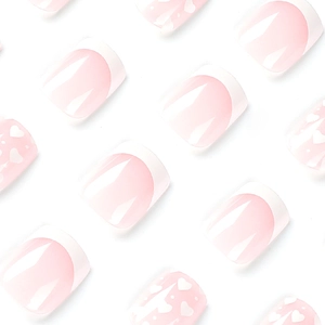 Pink and white gradient French press-on nails with white heart patterns and glossy finish