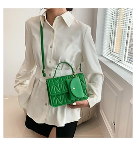 Detail of green quilted crossbody bag featuring a detachable mini envelope pouch