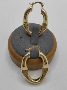 Detailed view of gold ripple oval earrings on a grey display base showing metallic texture