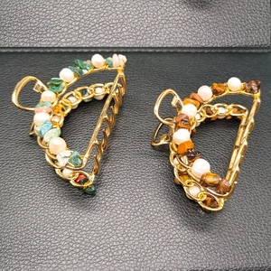 Detail of gold hair claw clip set with green pink crushed stones and white pearls