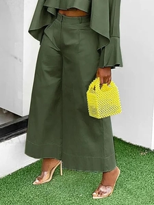 Detail of army green wide-leg trousers and matching top with beaded handbag