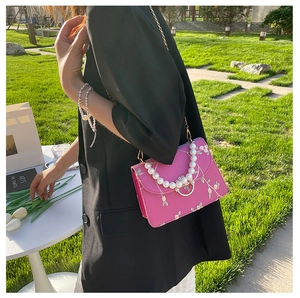 Detail of pink floral embroidery and luxury pearl handle on a flap crossbody bag
