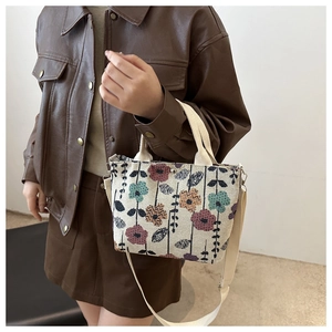 Detail of canvas tote bag with woven floral pattern and adjustable crossbody strap