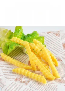 Close-up of realistic PVC crinkle cut fries model with green lettuce leaf on newspaper