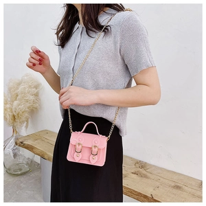 Pink mini jelly crossbody bag with gold chain strap shown on model in a cozy setting