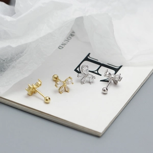 Macro view of gold and silver S925 sterling silver bow earrings with sparkling zircons