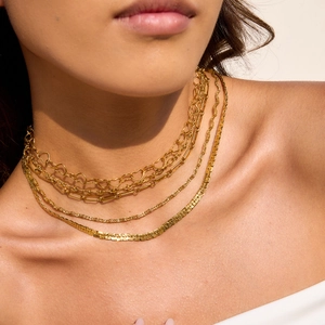 Nahaufnahme einer mehrlagigen goldenen Schlangenkette und Gliederkette für Damen