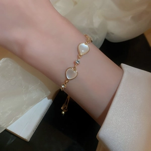 Detail of adjustable gold-plated bracelet with opal hearts and sparkling crystal stones