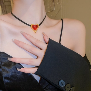 Close-up of heart-shaped red pendant choker necklace with golden textured frame