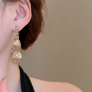 Close-up of champagne gold droplet earrings with crystals worn by a model