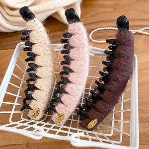 Trois barrettes banane en maille pelucheuse en beige rose et marron dans un panier blanc