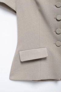 Detailed macro view of the light grey blazer's pocket flap and elegant round buttons