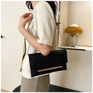 Close-up of black pleated evening clutch bag with gold metal trim and chain strap