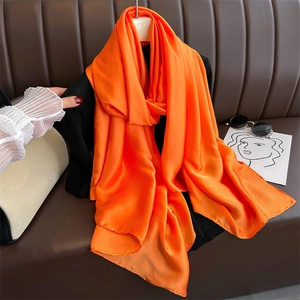 Detail of vibrant orange satin scarf draped over clothes with silky texture and soft sheen